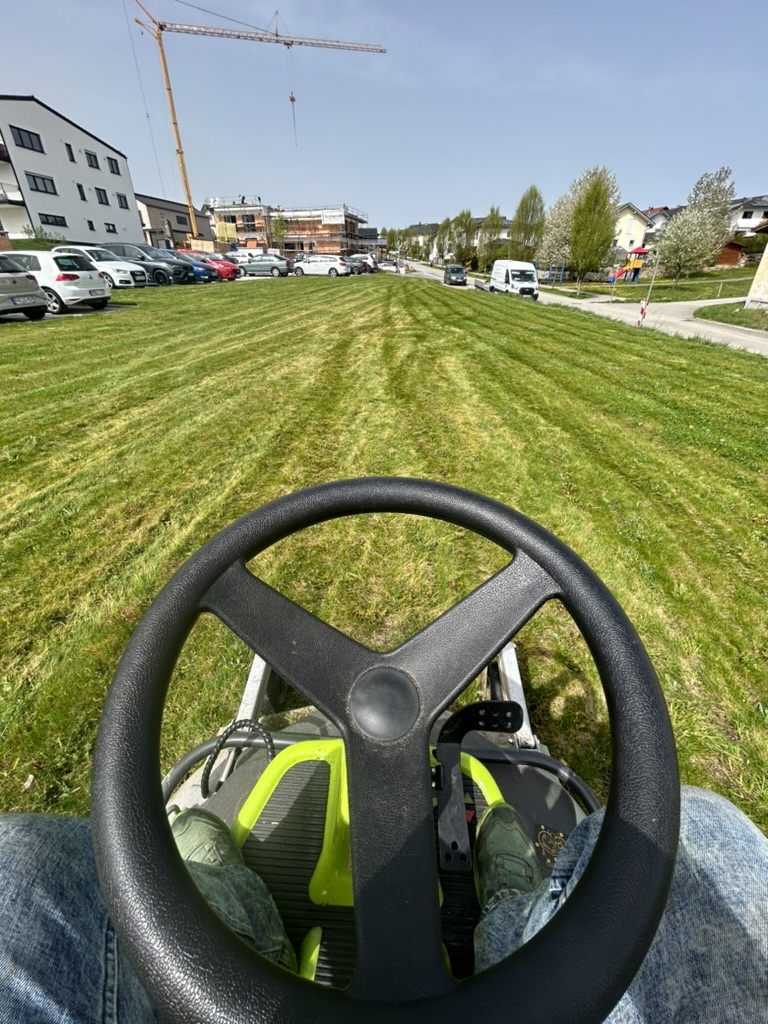 Maschinelle Rasenpflege auf einer großen Grünfläche einer Wohnanlage