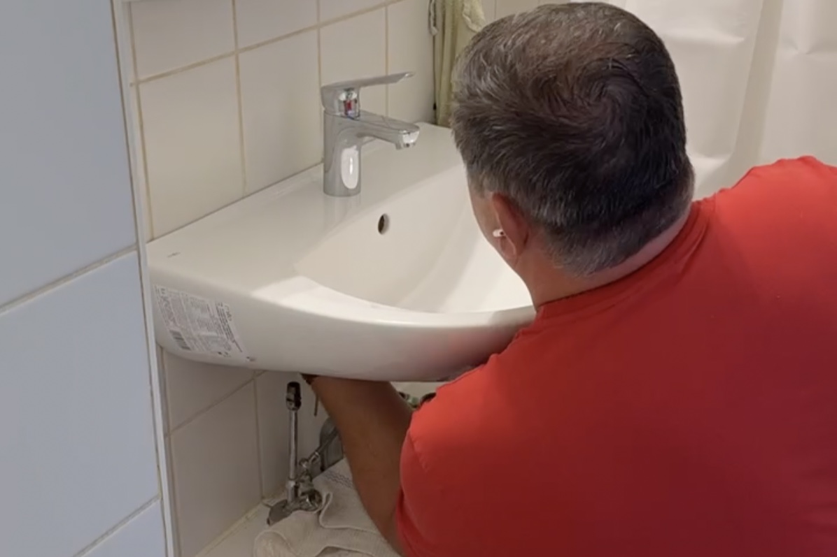 Mitarbeiter bei einer Reparatur an Waschbecken und Anschlüssen im Badezimmer
